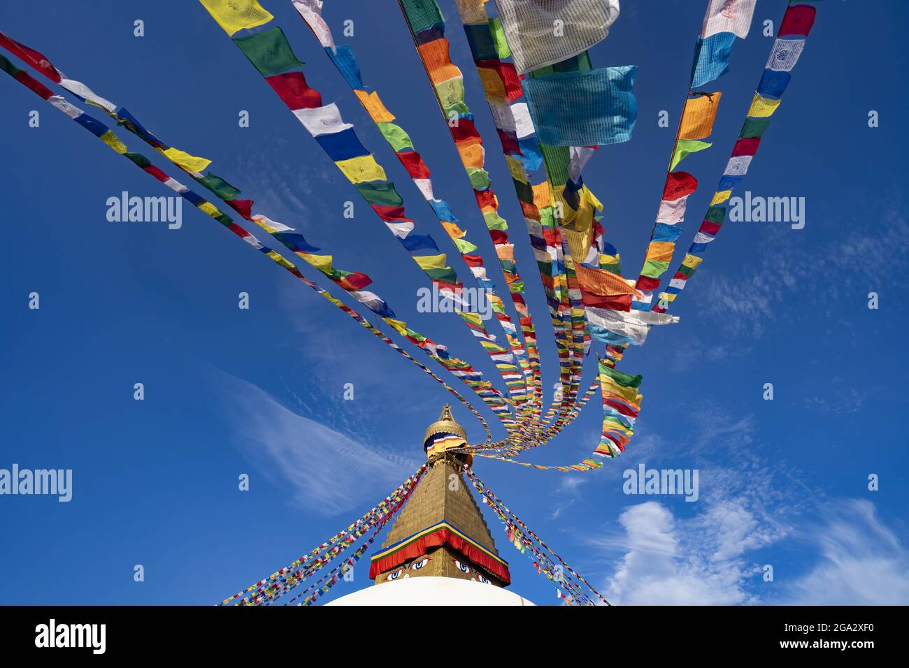 Bandiere di preghiera colorate appese alla guglia dorata del più grande stupa buddista tibetano in Nepal a Boudhanath superb di Kathmandu Foto Stock
