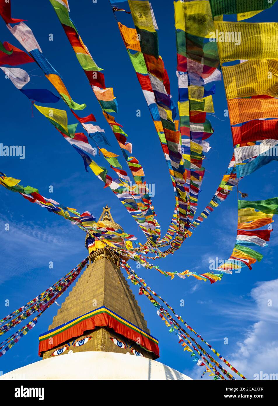 Bandiere di preghiera colorate appese alla guglia dorata del più grande stupa buddista tibetano in Nepal a Boudhanath superb di Kathmandu Foto Stock
