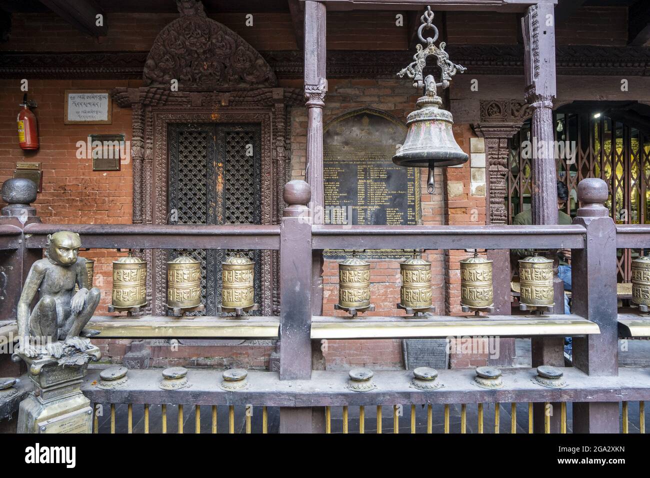 Figura di scimmia di ottone accanto al balcone con ruote di preghiera e campana in Kwa Bahal Tempio d'Oro nella città vecchia di Patan o Lalitpur costruito nel... Foto Stock