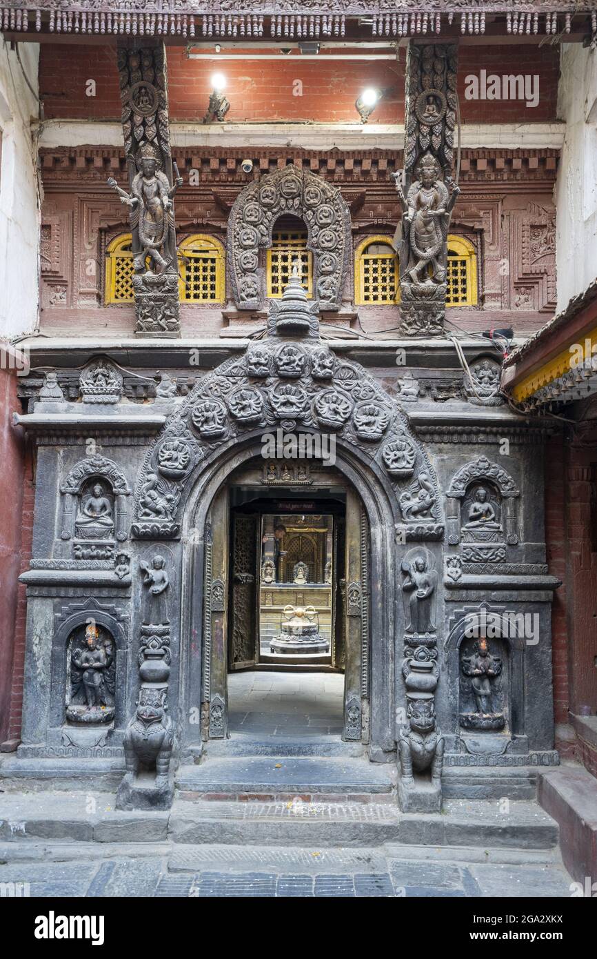 Sculture ornate circondano l'ingresso ad arco del tempio d'oro di Kwa Bahal nella città vecchia di Patan o Lalitpur costruito nel XII secolo ... Foto Stock