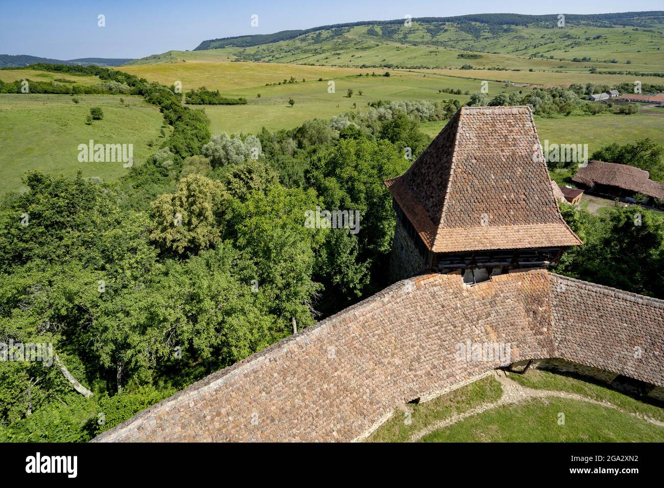 Tetto della Chiesa sassone fortificata di Viscri con le sue mura di pietra e panoramica del villaggio; Viscri, Contea di Brasov, Transilvania, Romania Foto Stock