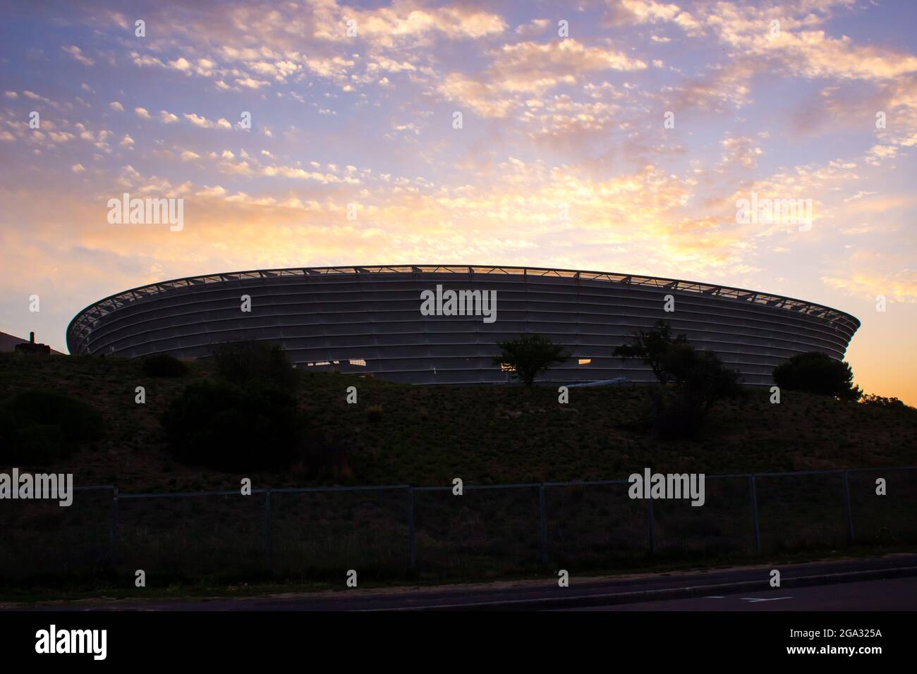 Silhouette dello stadio Green Point, Città del Capo, Sud Africa, al tramonto, con le nuvole colorate in una tonalità dorata. Questo è stato uno degli stadi costruiti Foto Stock