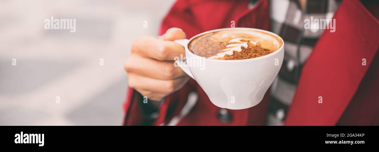 Latte art donna che tiene bere al caffè all'aperto. Caffetteria City Lifestyle banner panorama closeup della tazza cappuccino con tenuta a mano. Foto Stock