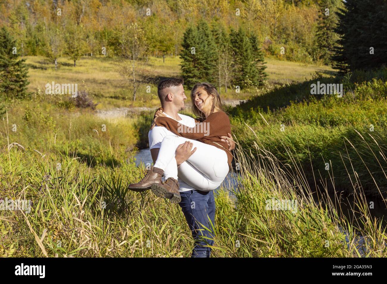 Marito e moglie trascorrono del tempo di qualità all'aperto vicino a un ruscello in un parco cittadino; Edmonton, Alberta, Canada Foto Stock