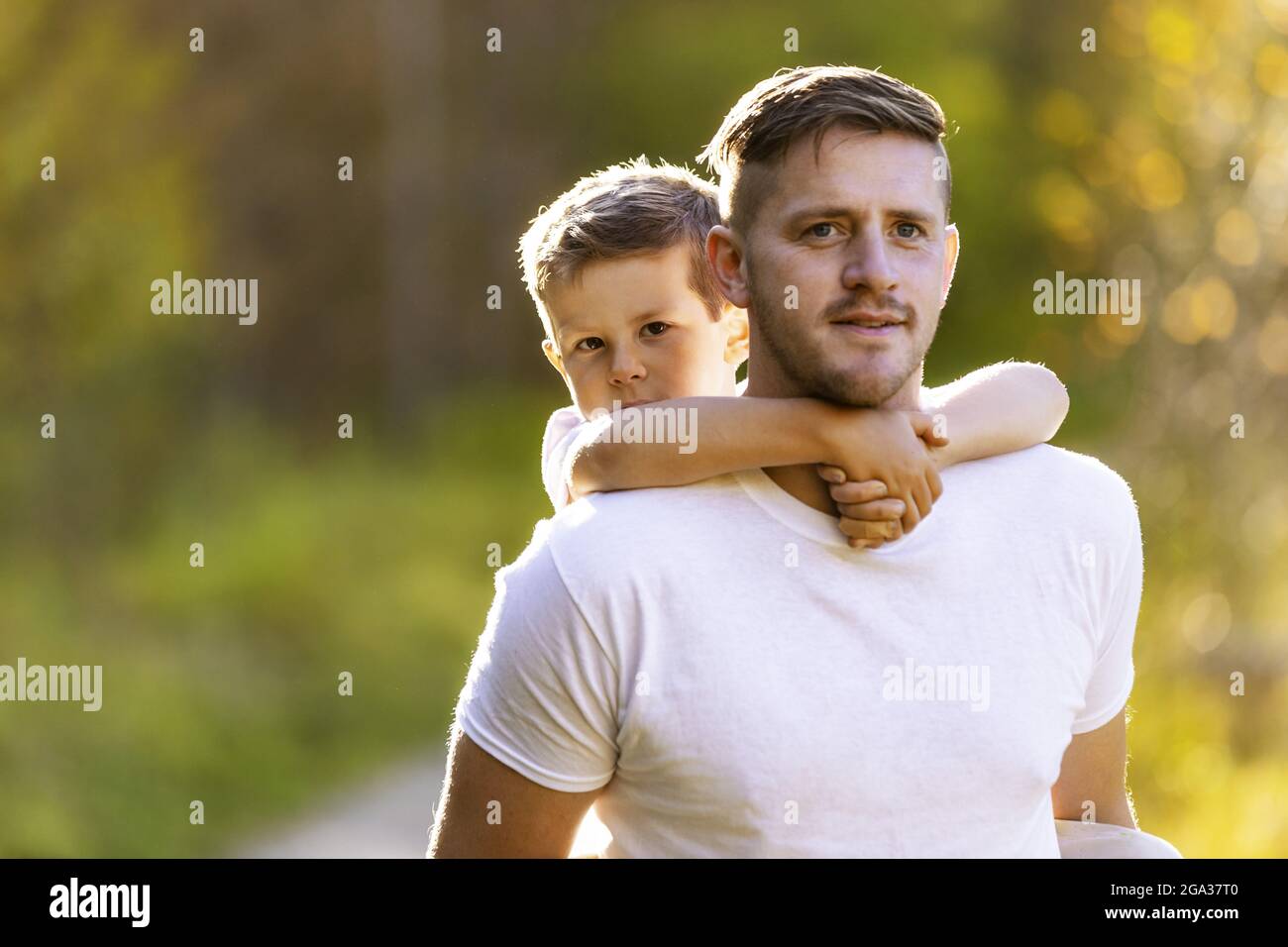 Un padre che riporta il figlio Piggy durante una gita in famiglia in un parco cittadino durante la stagione autunnale; Edmonton, Alberta, Canada Foto Stock