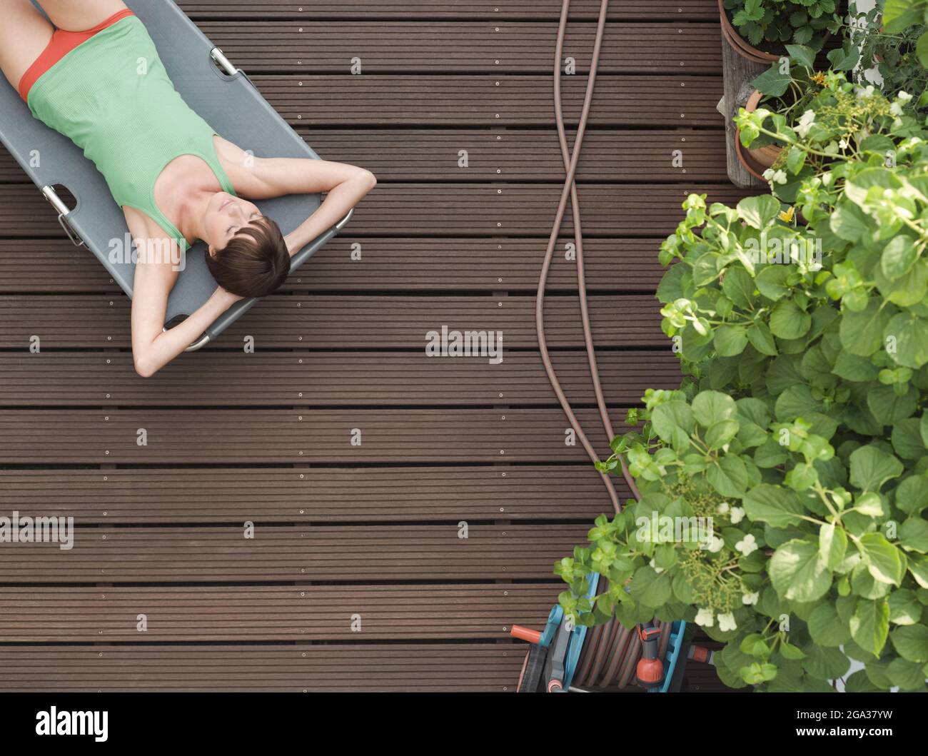 Giovane donna che si rilassa su una sedia a sdraio in un costume da bagno; Germania Foto Stock