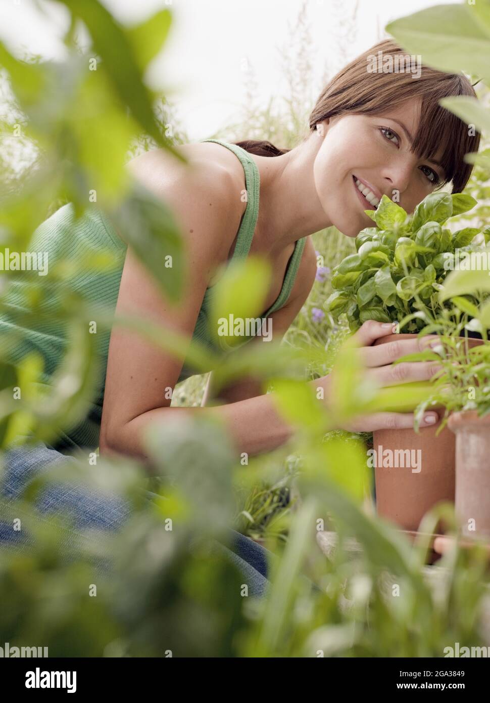 Donna all'aperto con piante in vaso guardando la macchina fotografica; Germania Foto Stock