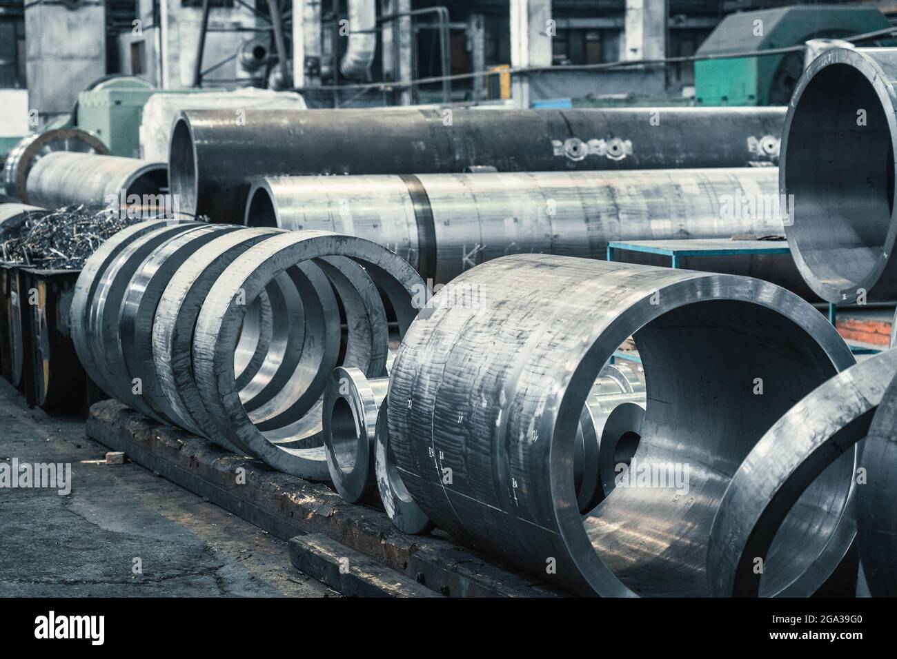 Grandi tubi in metallo rotondi in officina. Produzione di tubazioni o tubi di acciaio per l'industria pesante. Foto Stock