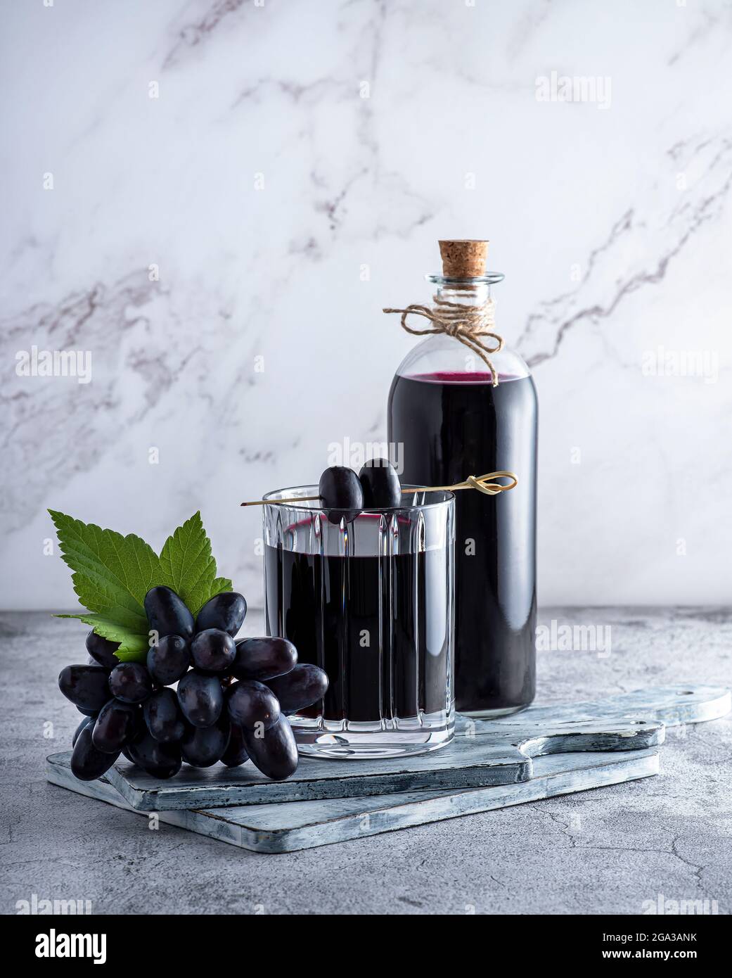 Fotografia di succo d'uva, vino rosso, uva, bicchiere, bottiglia su sfondo marmoreo Foto Stock