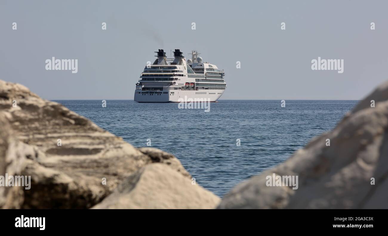 Nave da crociera Lusury sul mare, vista da dietro le bianche rocce costiere Foto Stock
