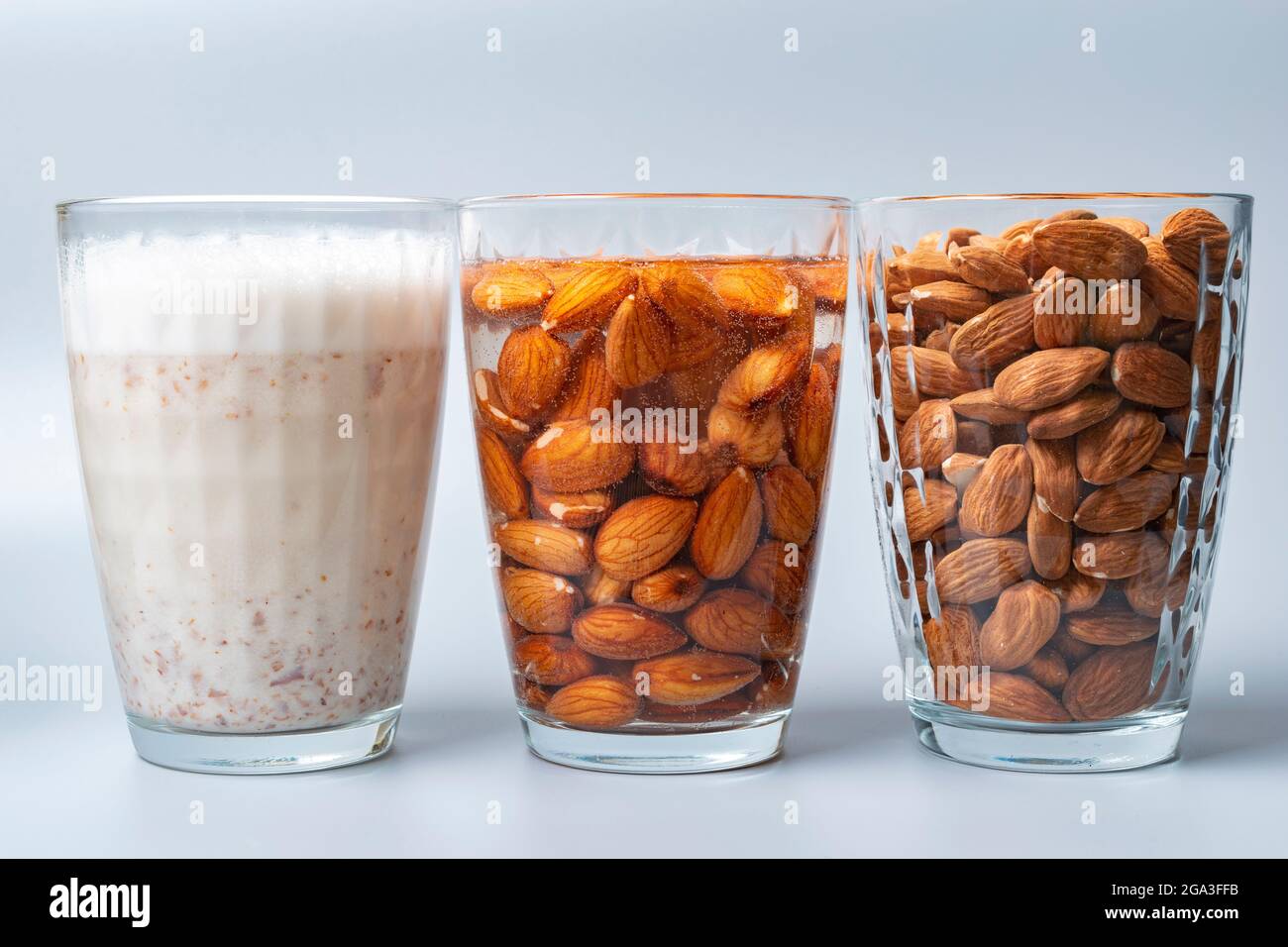 Bicchieri con mandorle secche e bagnate e latte di mandorle. Mostrare gli ingredienti necessari per preparare il latte di mandorle. Foto Stock