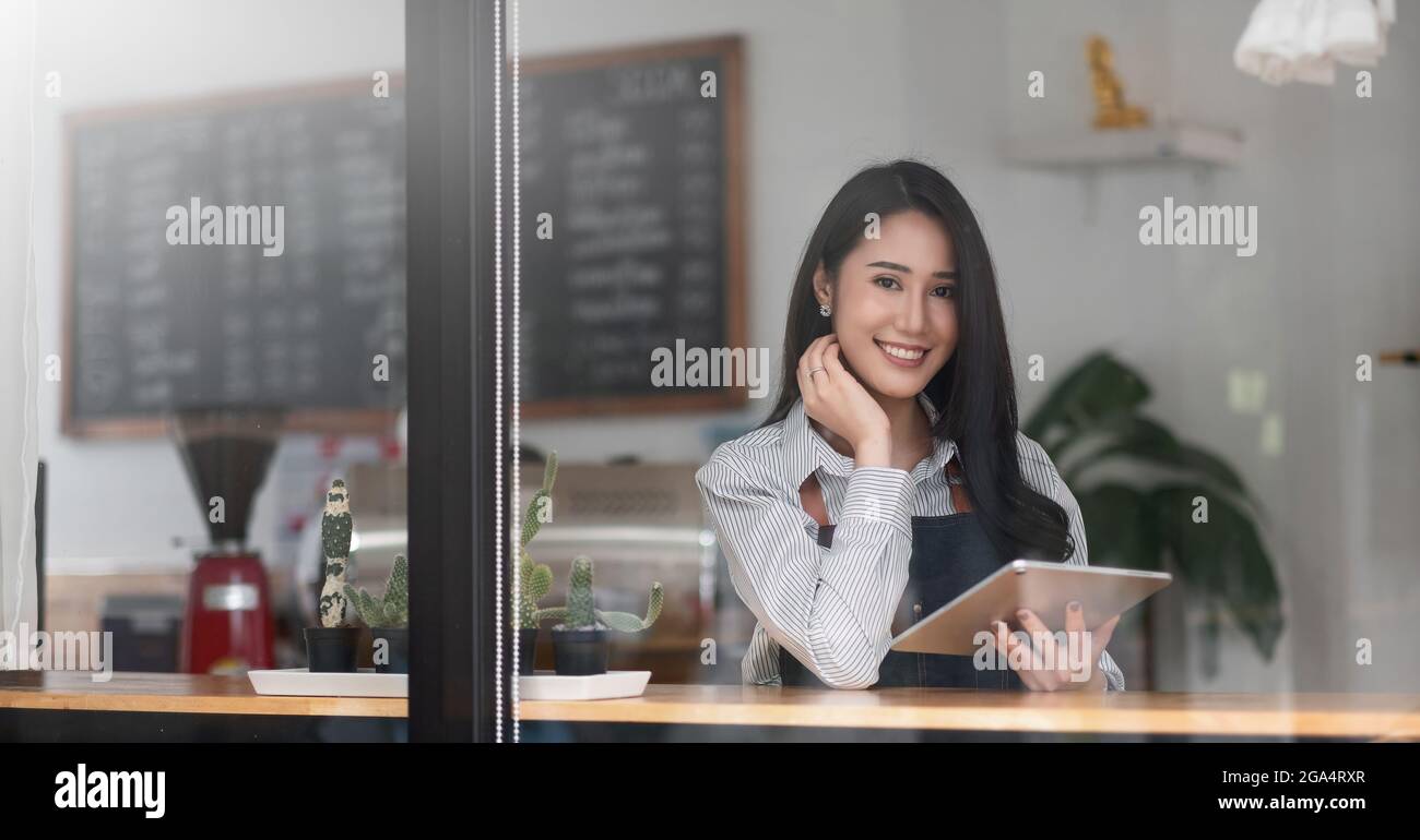 Allegro giovane donna asiatica proprietario tenere tablet digitale mentre si trova nel suo bar, giovane imprenditore concettuale Foto Stock