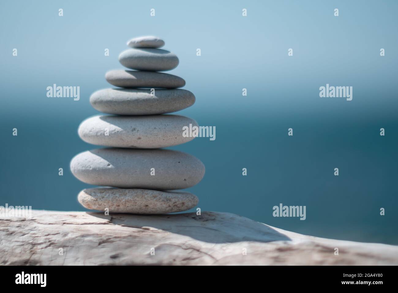 Equilibrata piramide di ciottoli sulla spiaggia in una giornata di sole. Abstract Sea bokeh sullo sfondo. Messa a fuoco selettiva. Pietre Zen sulla spiaggia di mare, meditazione Foto Stock