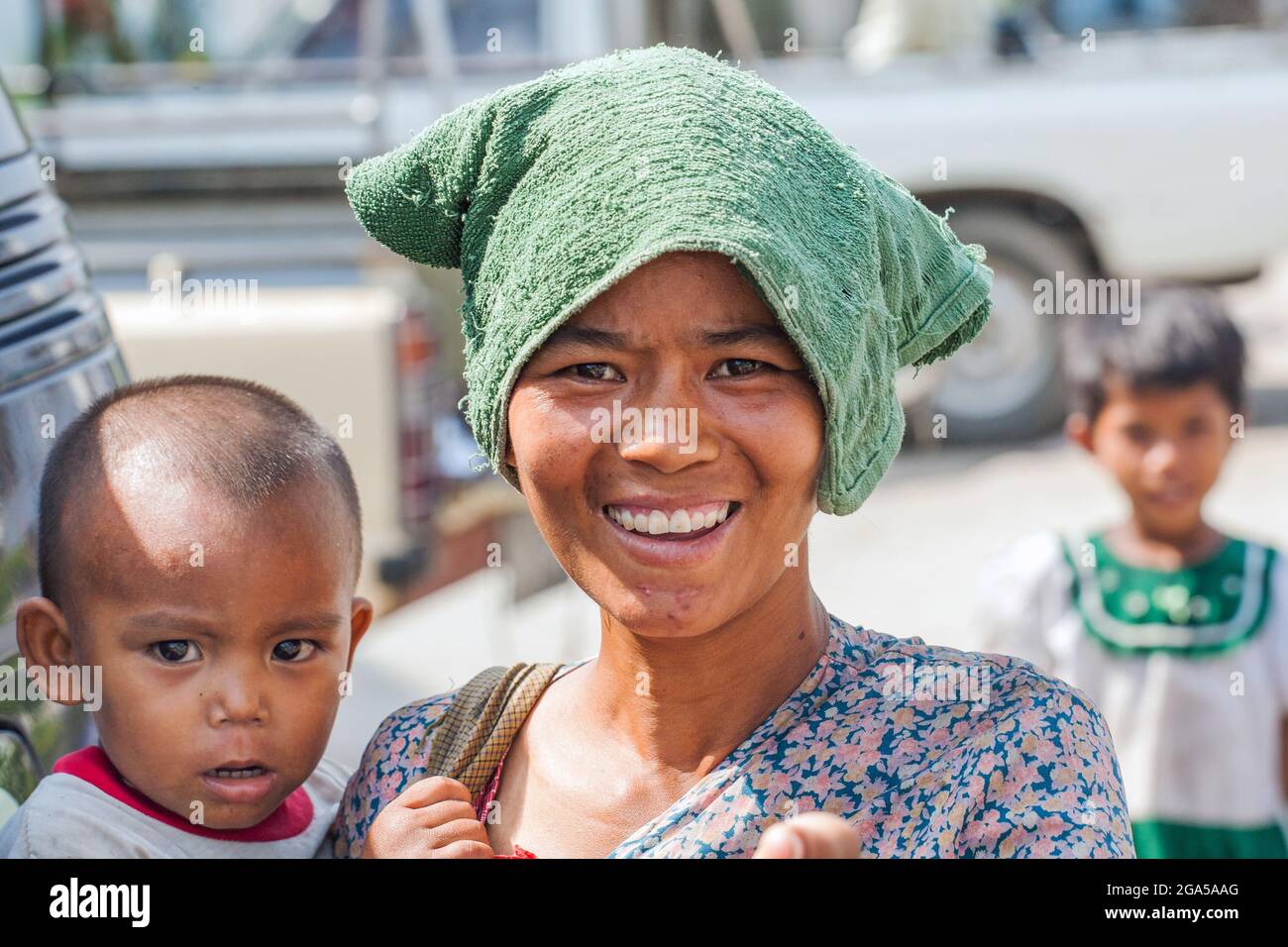 Bella giovane madre birmana con asciugamano sulla testa tiene il bambino in armi, Mandalay, Myanmar Foto Stock