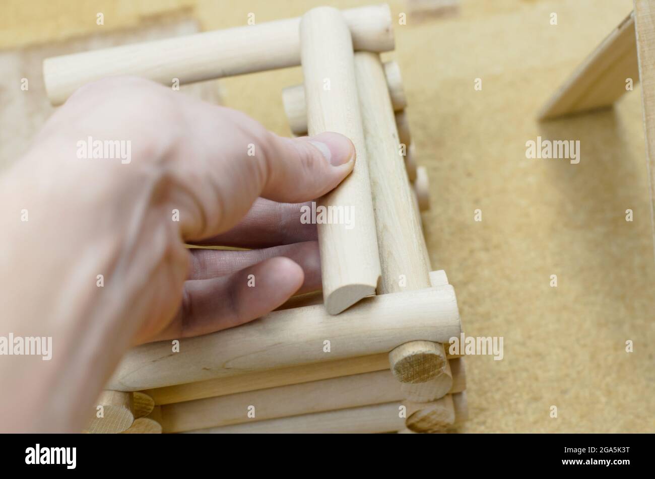 La mano dell'uomo assembla una casa da un kit di costruzione di legno Foto Stock