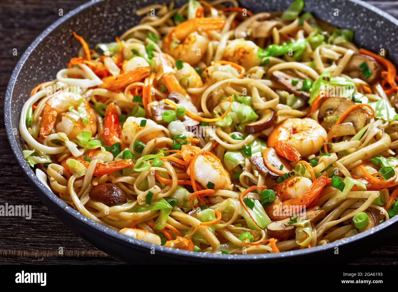 Gamberi Yaki Udon, fritti in padella di udoni con gamberetti, cavolo, funghi di castagno, cipolla primaverile, carote, mirin e salsa di soia, primo piano Foto Stock
