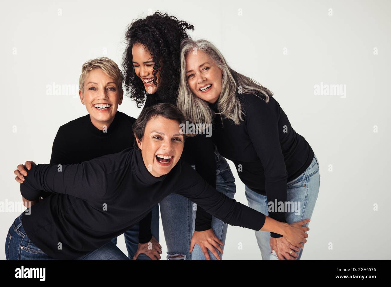 Corpo positivo donne di diverse età che celebrano il loro corpo naturale in uno studio. Quattro donne sicure e felici sorridono allegro mentre indossano je Foto Stock