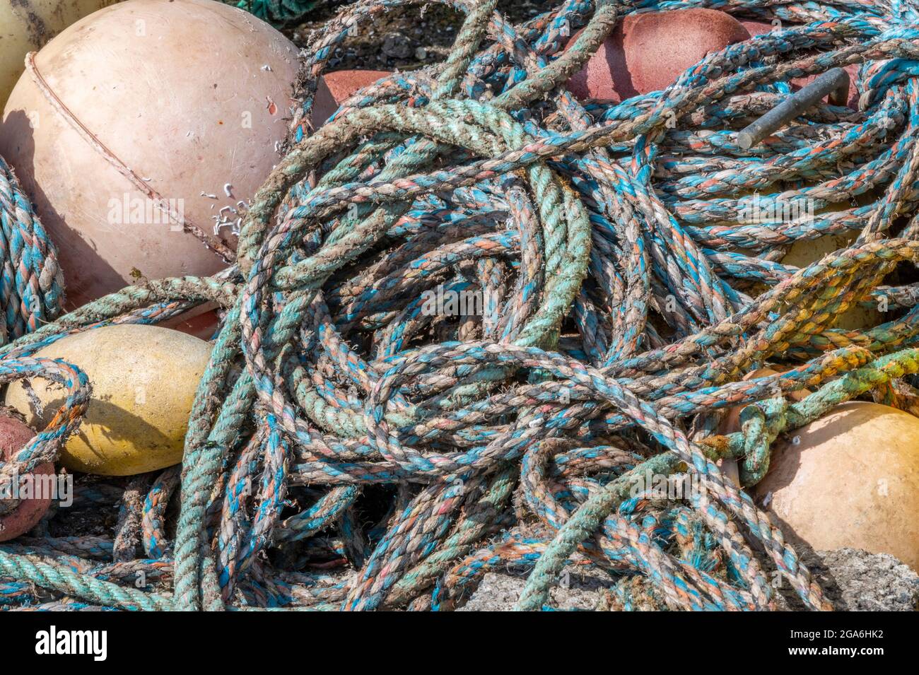 vecchie funi da pesca abbandonate e boe aggrovigliate e lasciate su una banchina. vecchie reti da pesca aggrovigliate e funi marittime e attrezzi. Foto Stock