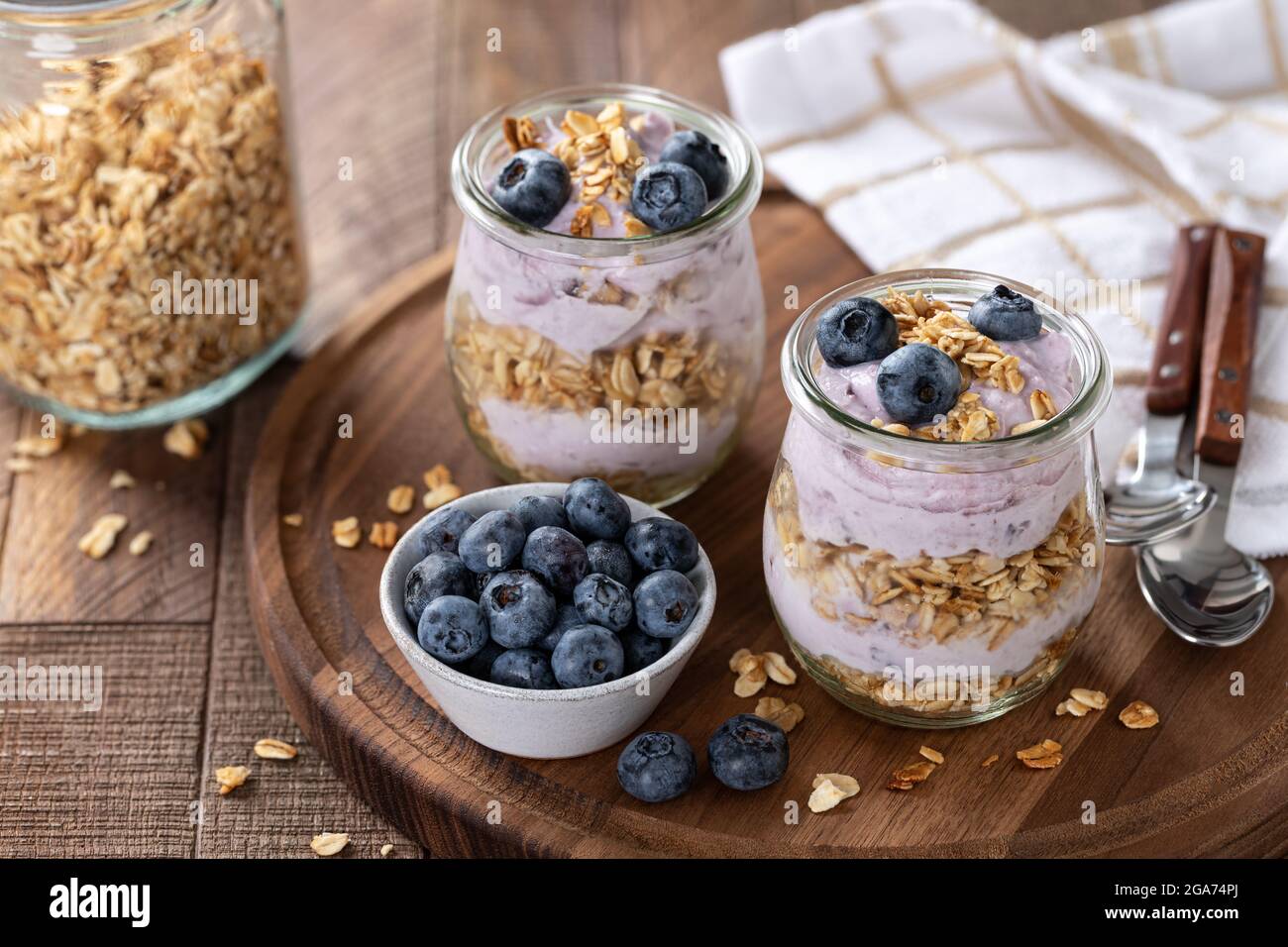 Parfait con mirtilli, muesli e yogurt in un bicchiere su un rustico tavolo di legno Foto Stock