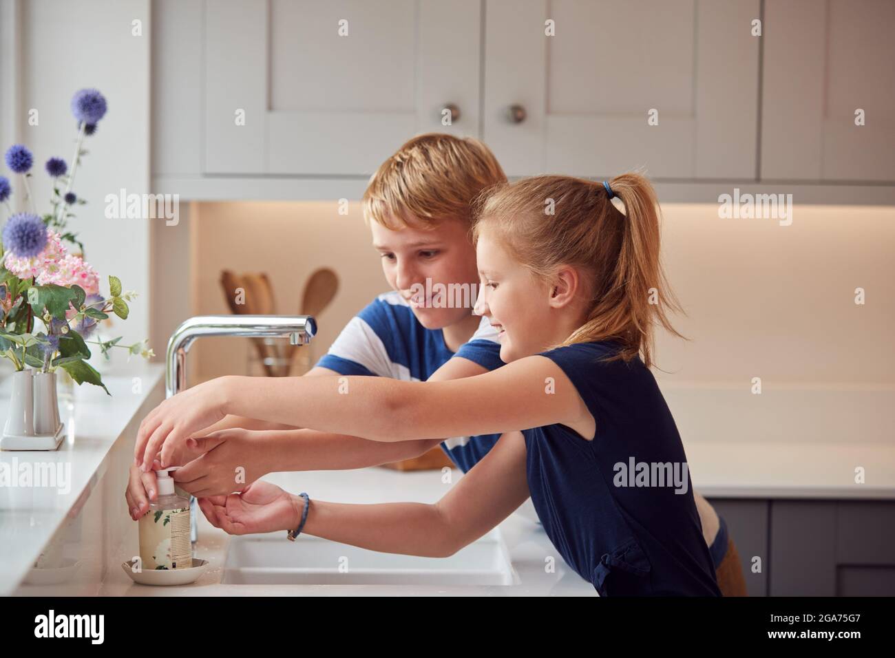 Due bambini lavando le mani con sapone a casa per prevenire la diffusione di infezione in Pandemic Salute Foto Stock