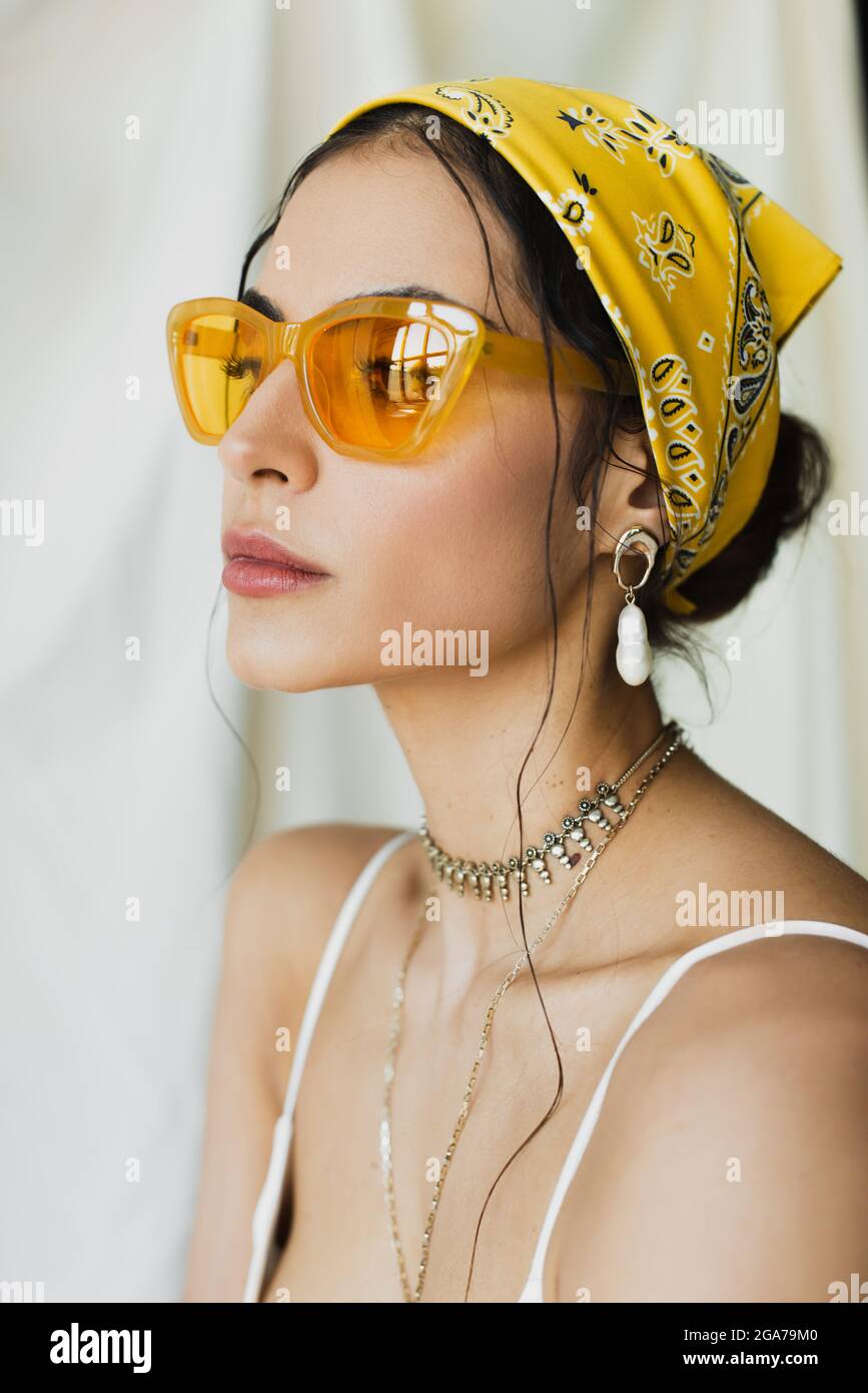 donna elegante con occhiali da sole alla moda e foulard giallo in posa su  bianco Foto stock - Alamy