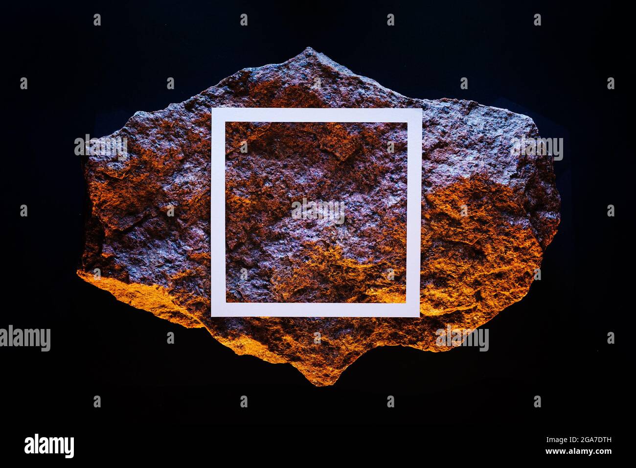 un meteorite giallo in uno spazio scuro con una cornice bianca e una luce fluorescente al neon. Foto Stock