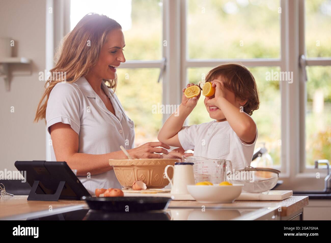 Madre e Figlio in Pajamas fare Pancakes in cucina a casa seguendo la ricetta sulla tavoletta digitale Foto Stock