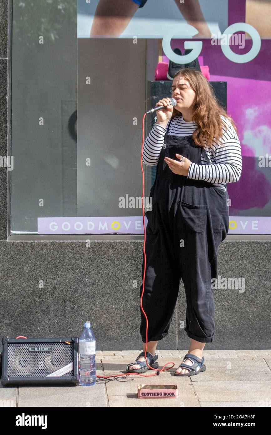 Ritratto di busker femminile che canta per soldi con amplificatore fuori negozio M&S a Preston, Regno Unito Foto Stock