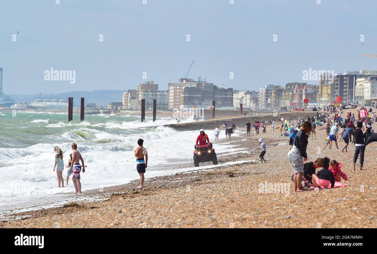 Brighton UK 29 luglio 2021 - UN bagnino ufficiale pattugola il litorale consigliando i visitatori dei pericoli mentre godono di una giornata soleggiata ma ventilata sulla spiaggia di Brighton con previsioni meteo non stabilite per continuare nei prossimi giorni in Gran Bretagna . : Credit Simon Dack / Alamy Live News Foto Stock