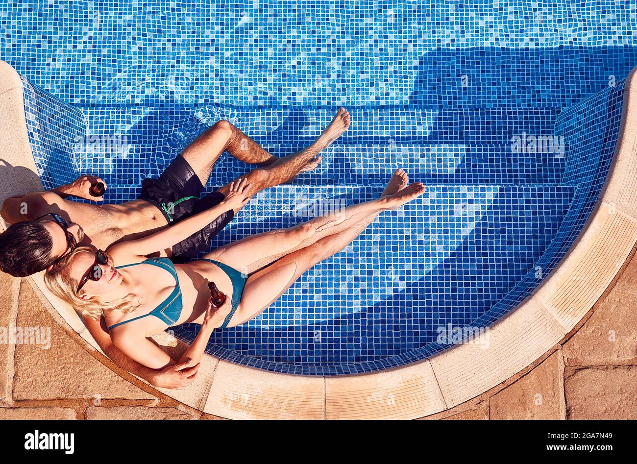 Foto in alto di coppia in costume da bagno relax in piscina all'aperto bere birra Foto Stock