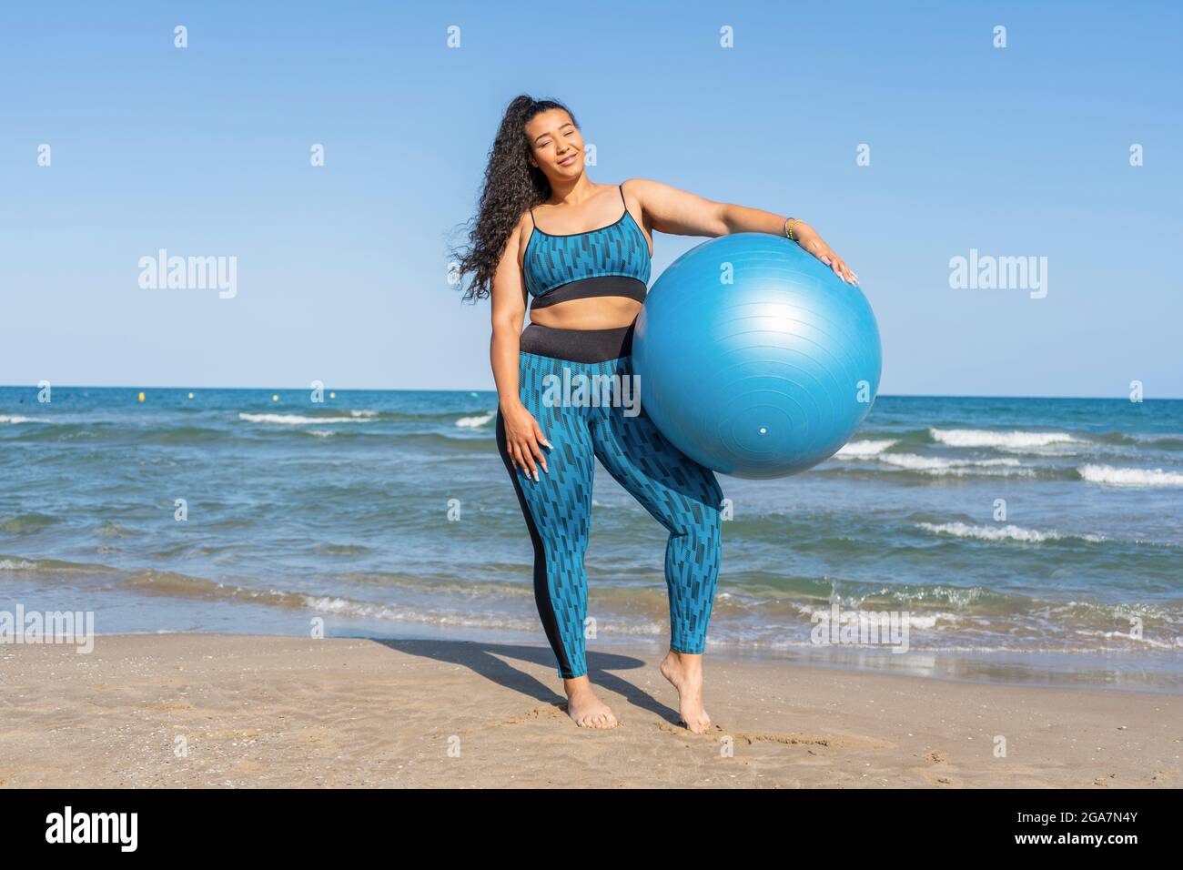 Allenamento fitness su Beach.Female tenendo una palla per esercizi di yoga. Foto Stock