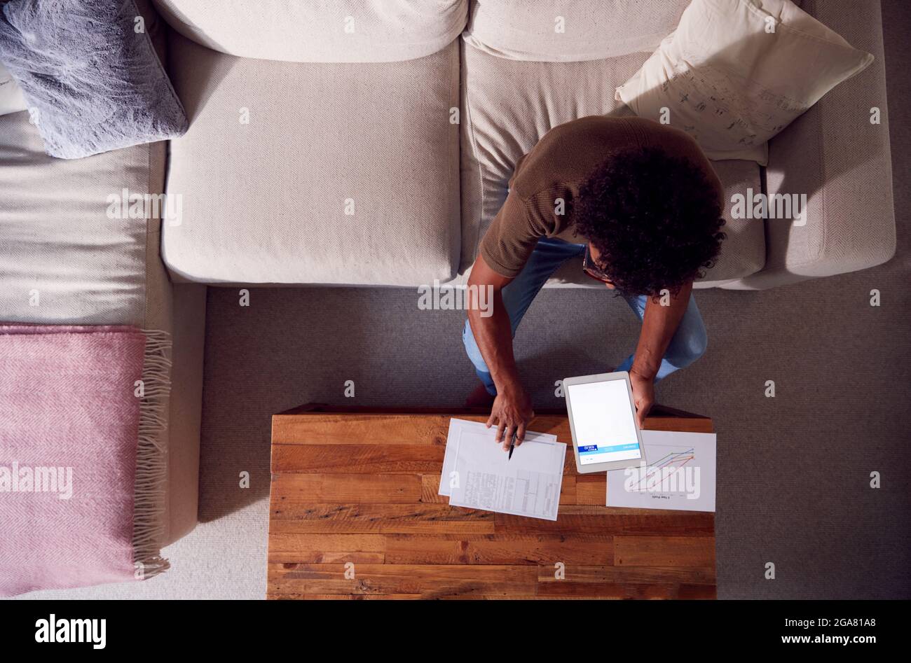 Overhead Shot of Man Working from Home seduta su divano Revisione di documenti utilizzando Digital Tablet Foto Stock
