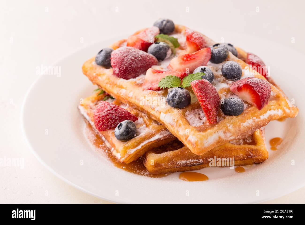 Waffle belgi con fragole, mirtilli e sciroppo, sana colazione fatta in casa, focalizzazione selettiva Foto Stock
