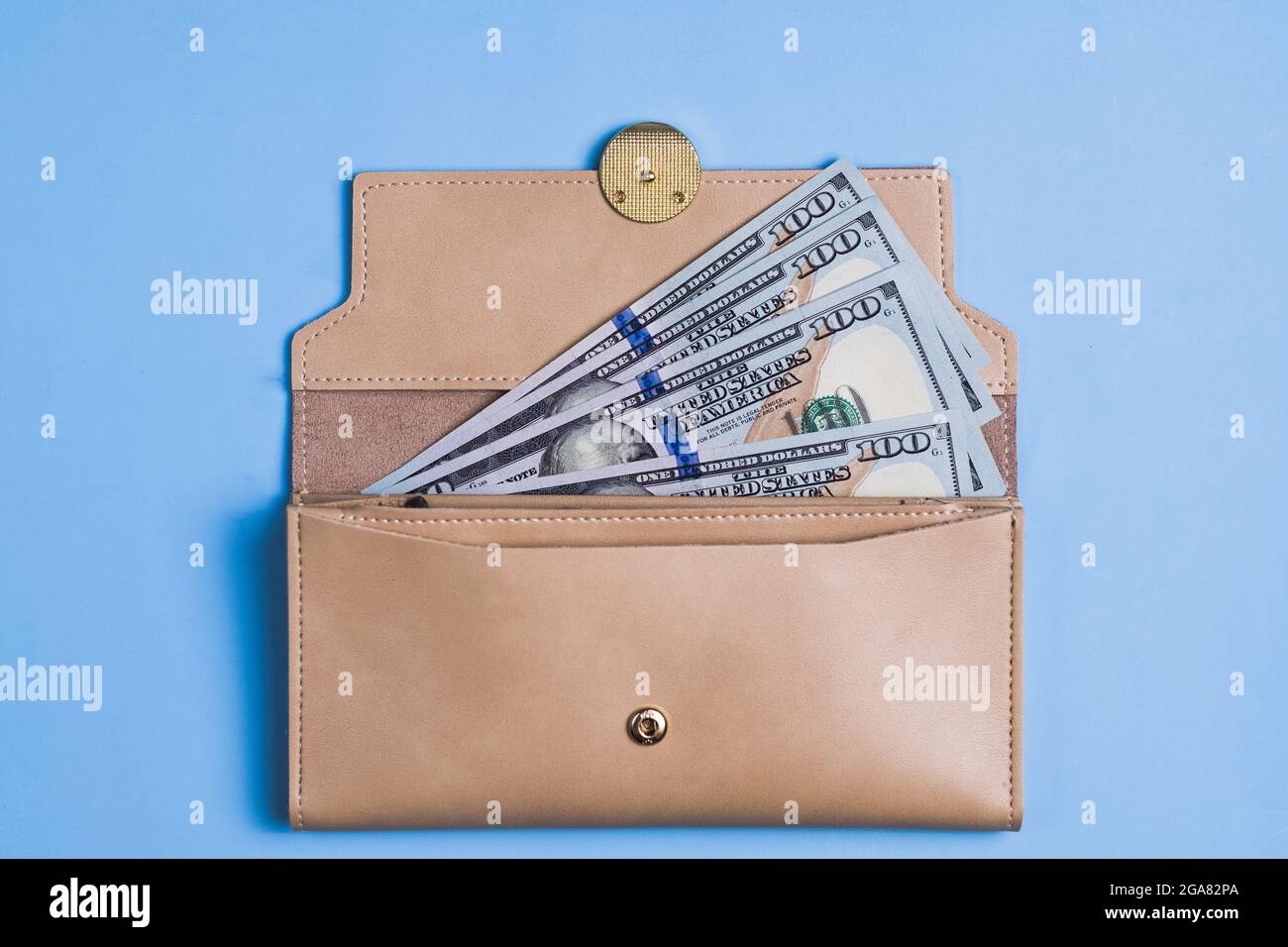 Banconote da 100 dollari con e portafoglio su sfondo blu. Foto Stock