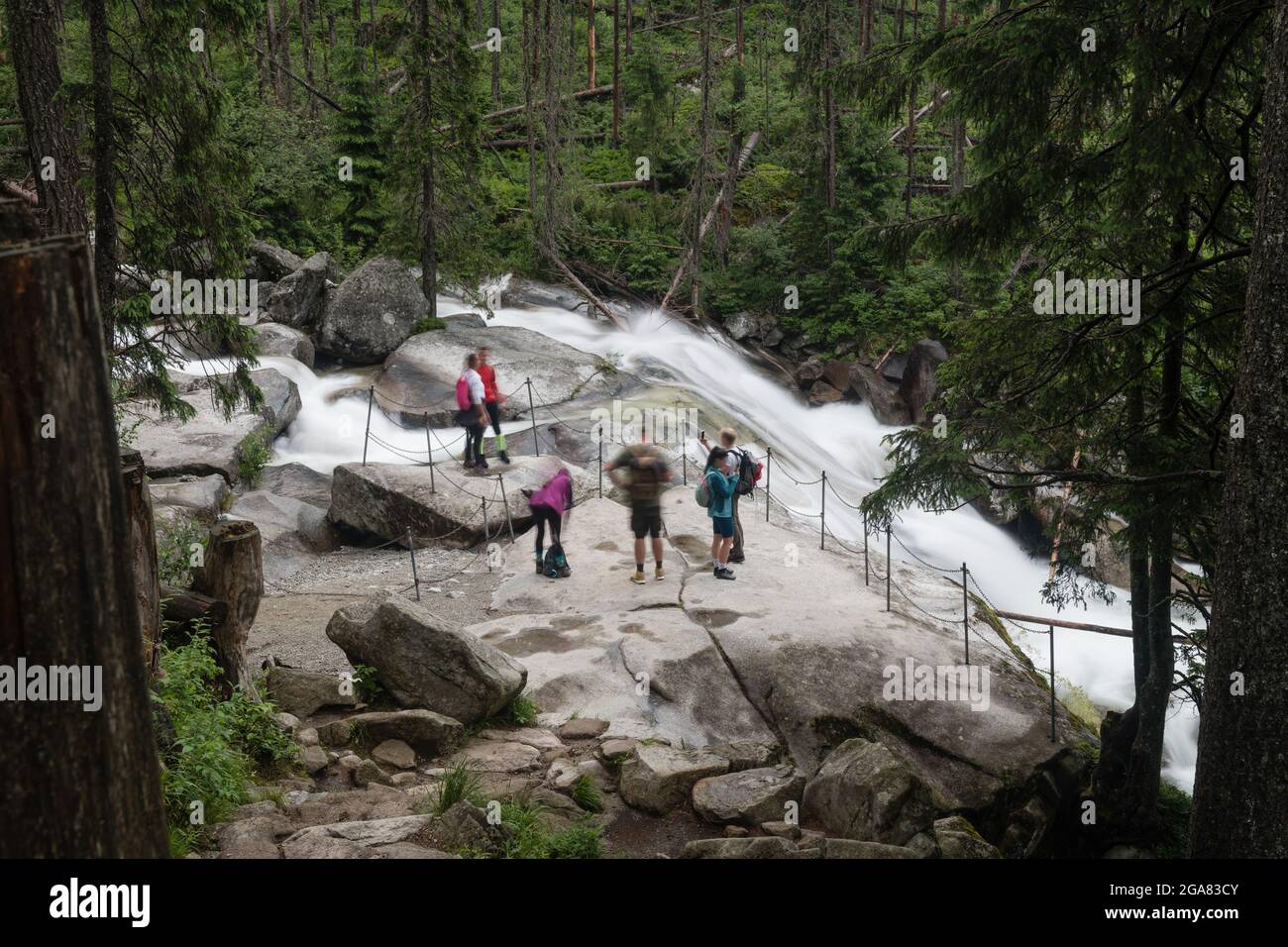 I turisti ammirano la bellezza delle cascate di acqua fredda nelle montagne di High Tatra, Slovacchia Foto Stock