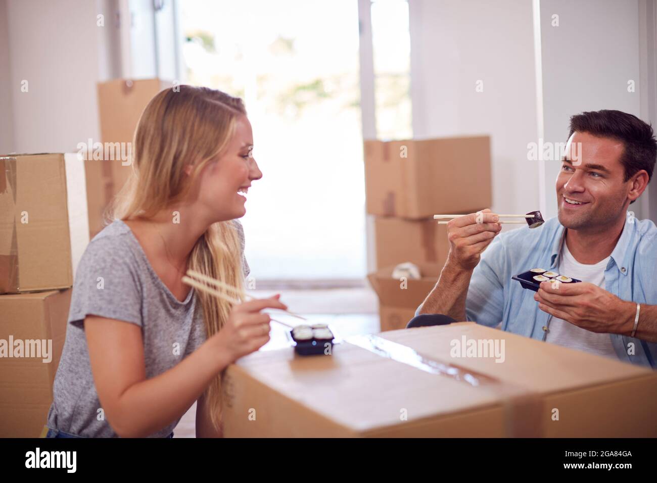 La coppia festeggia con il pasto di Sushi Takeaway seduto al piano di New Home in Moving Day Foto Stock