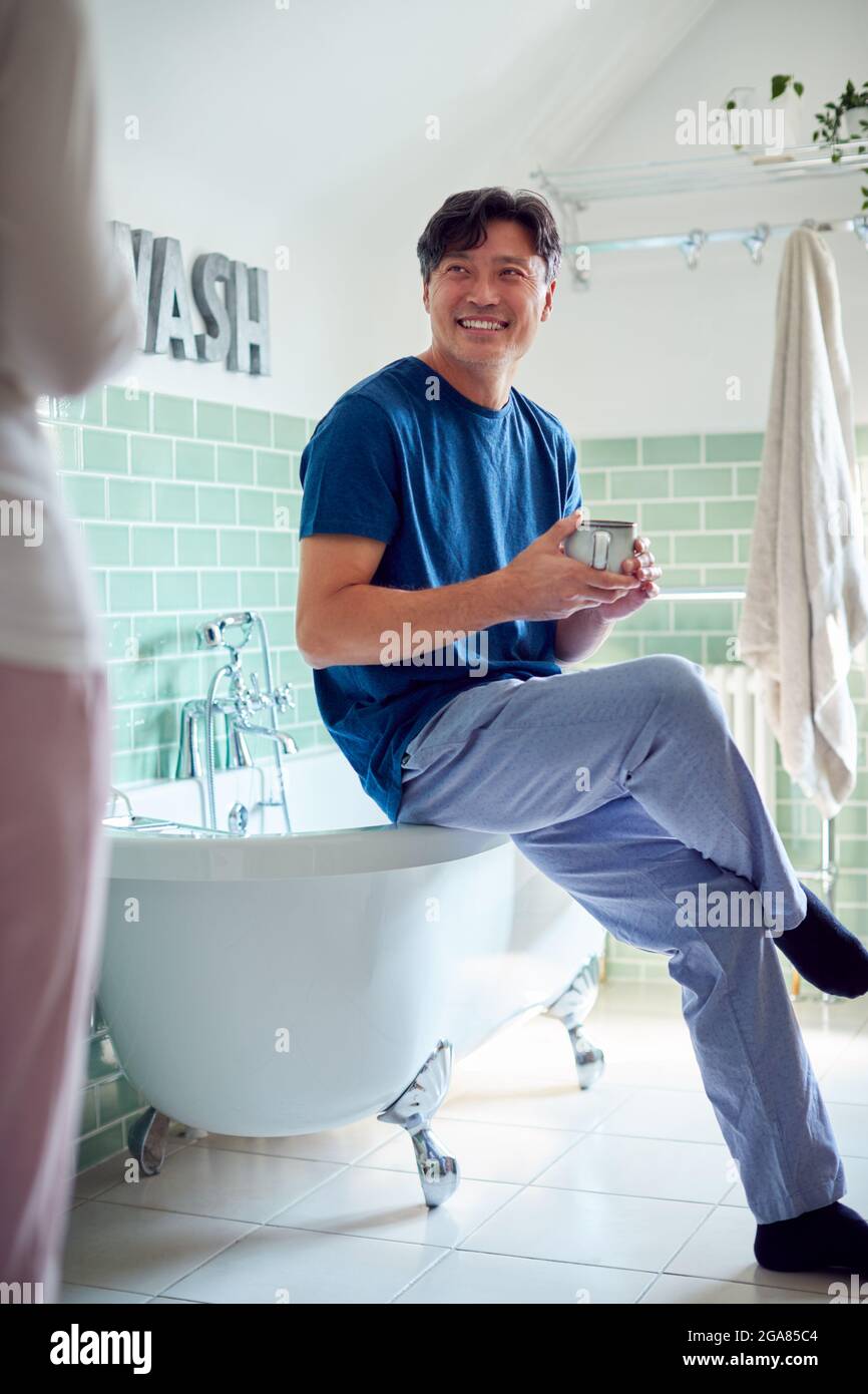 Coppia asiatica matura che indossa Pajama seduto in bagno godendo di bevande calde al mattino insieme Foto Stock