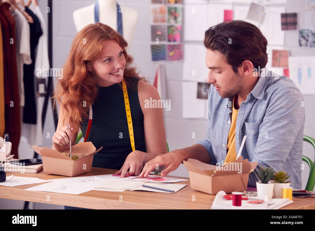 Uomini e donne di affari di moda che discutono i disegni sopra il cibo di Takeaway in studio Foto Stock