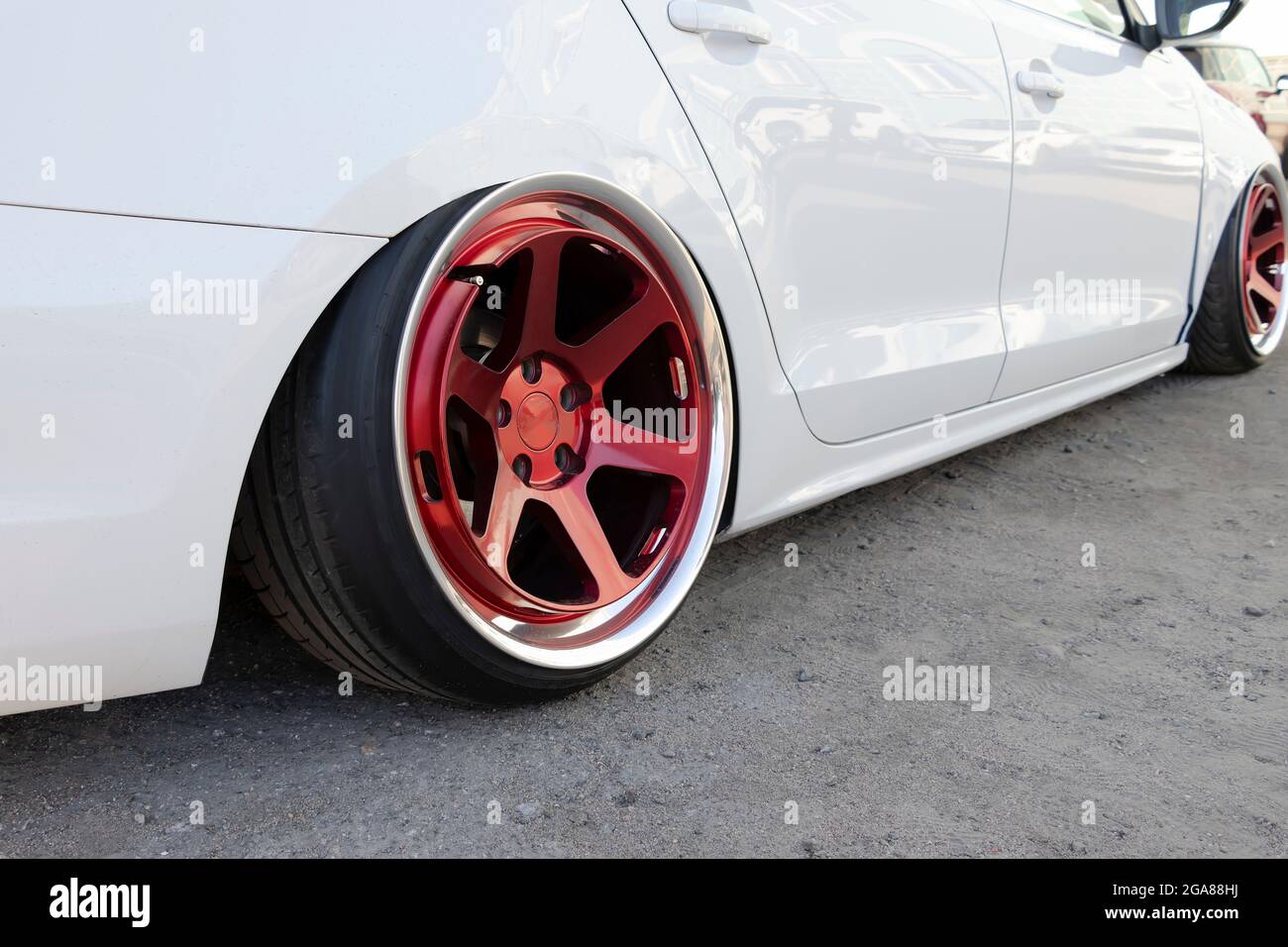 Auto bianca ottimizzata con sospensioni estremamente basse e ruote rosse. Messa a fuoco selettiva. Foto Stock