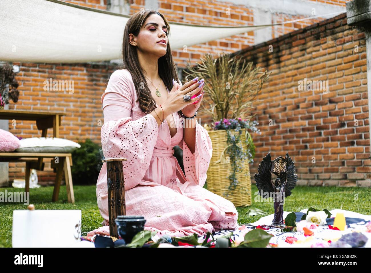 Ragazza latina seduta sulle gambe meditando all'aperto in terapia olistica Foto Stock
