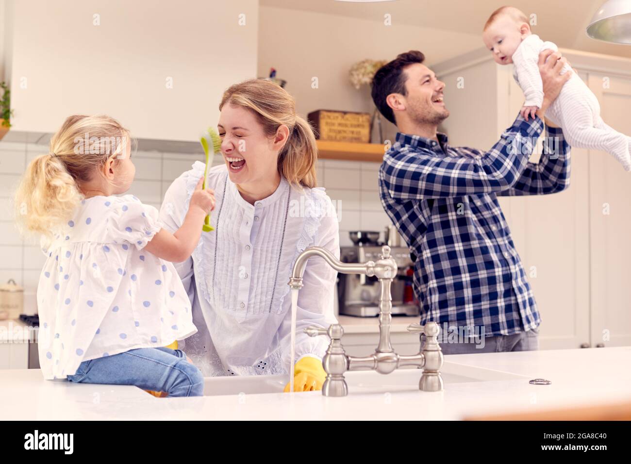 Famiglia sorridente divertirsi in cucina facendo lavatrice a Sink insieme Foto Stock