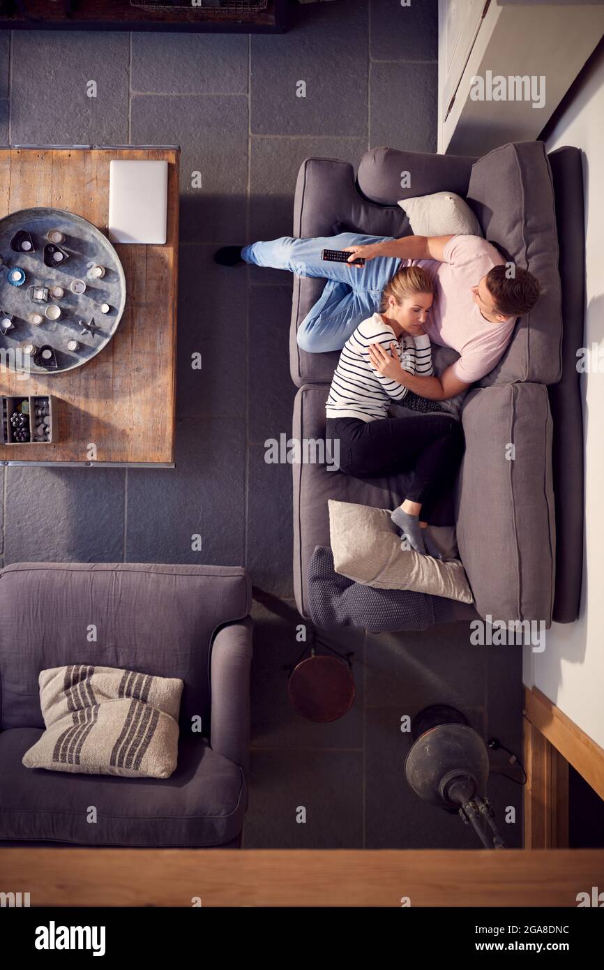 Vista dall'alto della coppia rilassante sul divano lounge con un pomeriggio di NAP a casa e guardando la TV Foto Stock