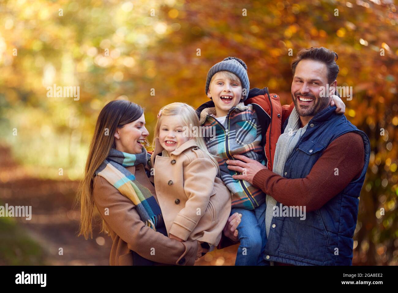 Ritratto di Famiglia con genitori maturi e due bambini camminando lungo la pista nella campagna autunnale Foto Stock