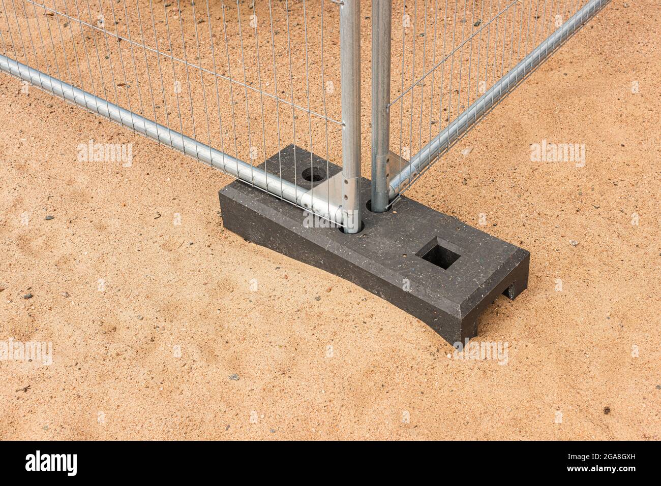 Il piede di un sistema provvisorio di recinzione che sta sulla sabbia Foto Stock
