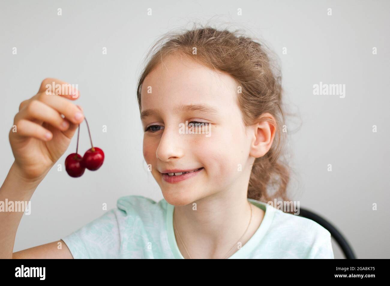 Felice sorprende la bambina tiene le ciliegie in mano. Concetto di alimentazione sana, dolci sani Foto Stock