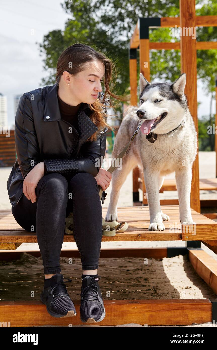 La ragazza del proprietario riposa con un cane Husky nel parco. Amicizia di un cane e di una donna Foto Stock