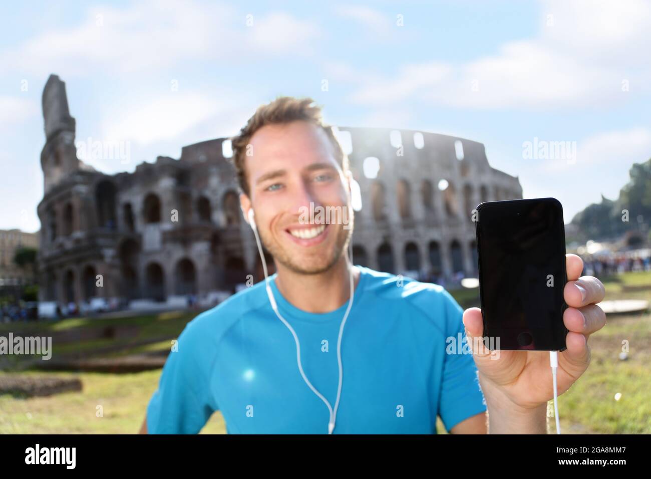 Felice Jogger che mostra smartphone contro il Colosseo Foto Stock