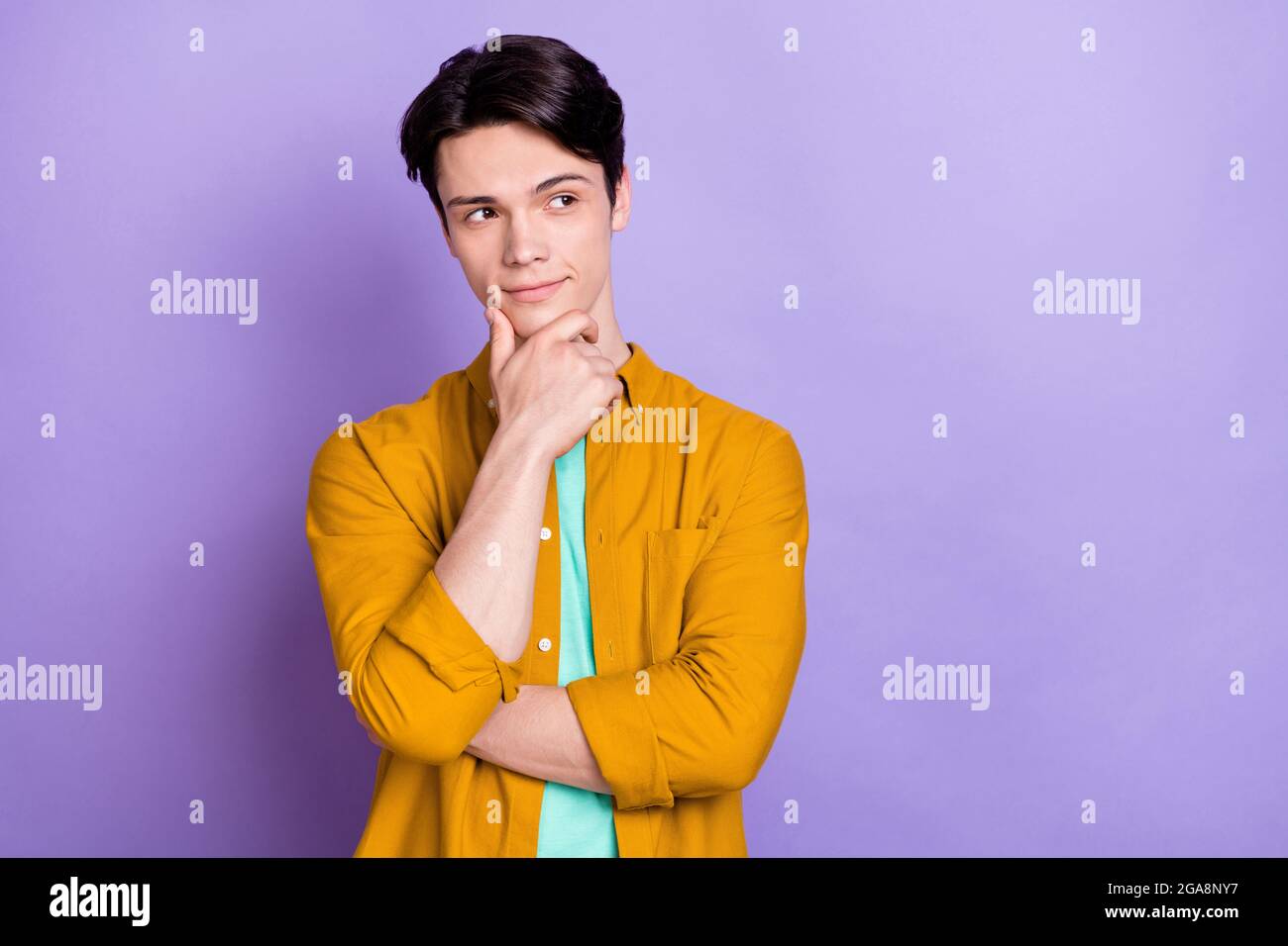 Foto del giovane bel uomo mano toccare il mento pensare profondo ponder sguardo vuoto spazio isolato su sfondo di colore viola Foto Stock