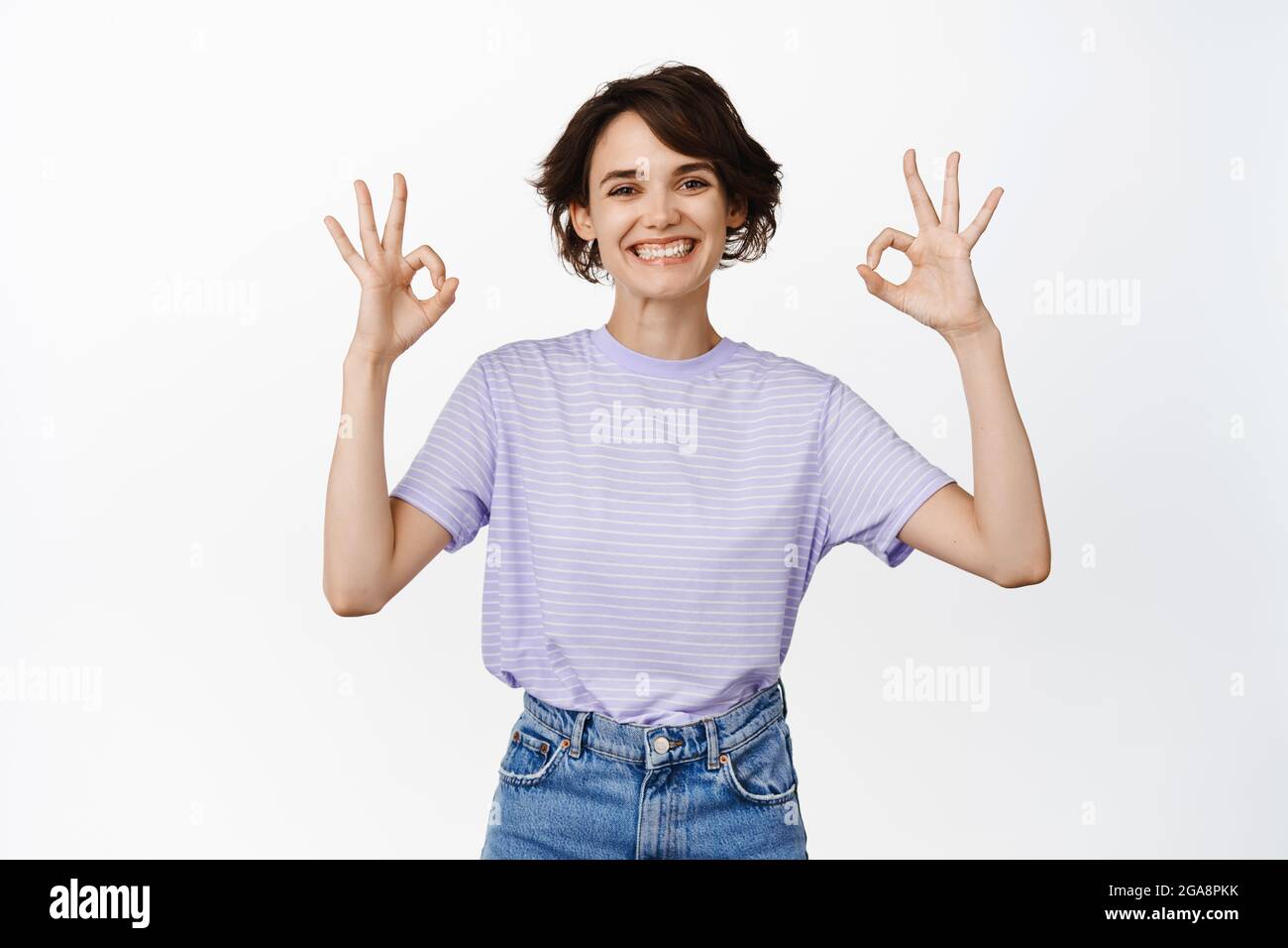 Non c’è problema. Sorridente giovane donna che mostra bene, OK segni in approvazione, come o d'accordo, garanzia di qualità, assicurato in servizio di azienda, lode smth bene Foto Stock