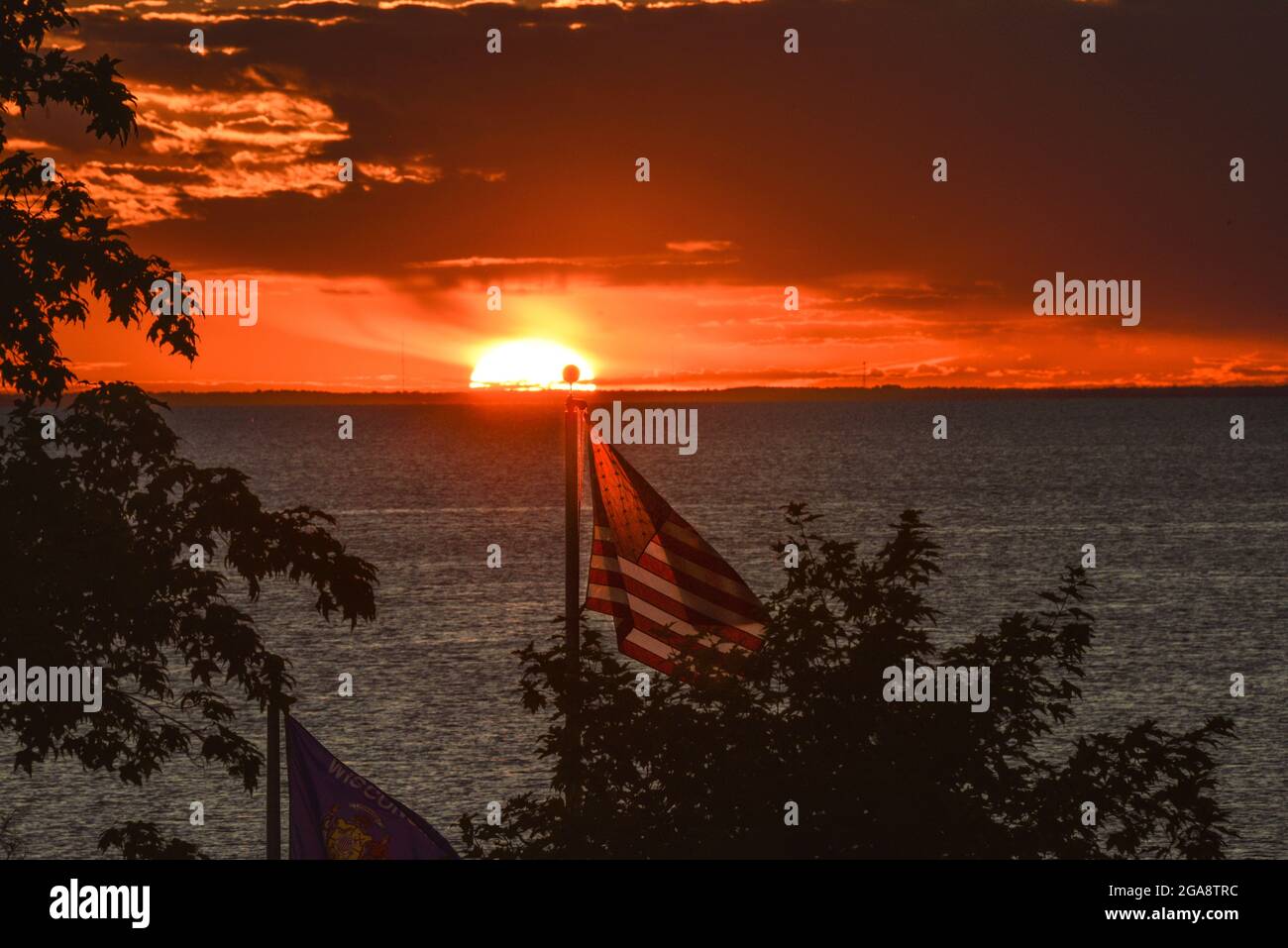 Bandiera americana che balzava nel vento con il magnifico tramonto su Green Bay (lago Michigan) visto dal parco di Egg Harbor, Door County, Wisconsin, USA Foto Stock